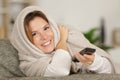 woman snuggled under blanket using remote control Royalty Free Stock Photo