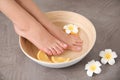 Woman soaking her feet in bowl with water, orange slices and flower on grey background, closeup. Royalty Free Stock Photo