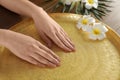 Woman soaking her hands in bowl with water and flowers on table. Spa treatment Royalty Free Stock Photo