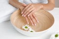 Woman soaking her hands in bowl with water and flowers on table. Spa treatment Royalty Free Stock Photo