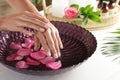 Woman soaking her hands in bowl of water and petals on table. Spa treatment Royalty Free Stock Photo