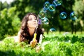 Woman and soap bubbles in park. Beautiful young girl lying on th Royalty Free Stock Photo