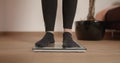 Woman in socks stepping on scale to see her weight