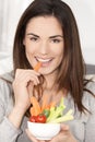 Woman on sofa eating vegetable salad