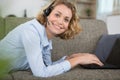 Woman on sofa wearing headset and using laptop Royalty Free Stock Photo