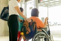 Woman with son and mother in wheelchair waiting for boarding at International airport.