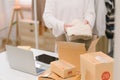 A woman sorting clothes and packing them into a cardboard box for selling online at her home . Business Owner concept Royalty Free Stock Photo