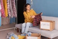 Woman sorting clothes sitting on sofa at home, packing cardboard donation box. Helping poor people. volunteering work Royalty Free Stock Photo