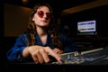 Woman sound engineer at the mixer in music studio. Woman in sunglasses and jeans behind mixing console in recording studio Royalty Free Stock Photo
