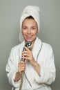 Woman spa model taking a shower and singing. Attractive woman in white bathrobe and towel on her head holding a shower Royalty Free Stock Photo