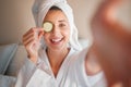 Woman, spa and selfie with cucumber on eye in comic portrait for wellness, self care and relax. Girl, fruit and face for