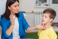 Woman speech therapist corrects speech defects in a boy in her office