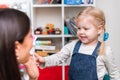 Woman speech therapist helps cute girl to learn correct pronunciation and literate speech