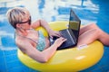 Woman spends time, has relax and work with laptop on the pool. People, summer and holiday concept Royalty Free Stock Photo