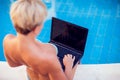 Woman spends time, has relax and work with laptop on the pool. People, summer and holiday concept Royalty Free Stock Photo