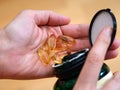 Woman spilling Omega softgel capsules out from a jar to her hand