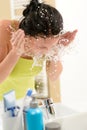 Woman splashing water on face in bathroom