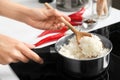 Woman with spoon stirring rice in saucepan, closeup