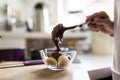 Woman spooning chocolate sauce onto a dessert