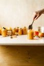 Woman spooning fresh homemade applesauce in glass jars on kitchen table