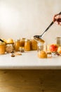 Woman spooning fresh homemade applesauce in glass jars on kitchen table