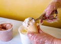 Woman spooning a scoop of ice cream into a waffle cone