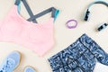 Woman sport bra, leggins, sneakers, headphones and fitness tracker on neutral background. Sport fashion concept. Royalty Free Stock Photo