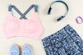 Woman sport bra, leggins, sneakers, headphones and fitness tracker on neutral background. Sport fashion concept. Royalty Free Stock Photo