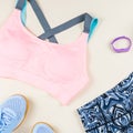 Woman sport bra, leggins, sneakers, headphones and fitness tracker on neutral background. Sport fashion concept. Royalty Free Stock Photo