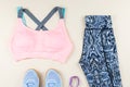 Woman sport bra, leggins, sneakers, headphones and fitness tracker on neutral background. Sport fashion concept.