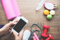 Woman in sport wear using mobile phone with fruits and sport equipments in background