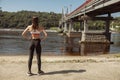 Woman in sports clothes looks at river standing on sand bank Royalty Free Stock Photo