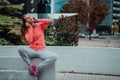 a woman in a sports outfit is resting in a city environment after a hard morning workout while using noiseless Royalty Free Stock Photo