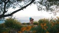 A woman in sportswear doing breating exercises on the yoga mat on a hill by the blue sea