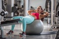 Woman in sportswear doing crunches on a fitness ball surrounded by workout machines in the gym Royalty Free Stock Photo