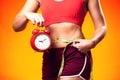 Woman in sportswear holding alarm clock and meter. People, fitness and healthcare concept Royalty Free Stock Photo