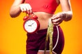 Woman in sportswear holding alarm clock and meter. People, fitness and healthcare concept Royalty Free Stock Photo