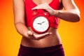 Woman in sportswear holding alarm clock. People, fitness and healthcare concept Royalty Free Stock Photo