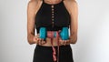 A woman with sportswear holds a dumbbell and measuring uniform in her hands - a sporty lifestyle