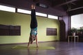 Woman in sportswear practicing yoga doing Adho Mukha Vrikshasana exercise, inverted tree pose, exercising on mat in room Royalty Free Stock Photo