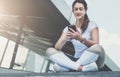 Woman in sportswear sitting in city street, relax after sports training, use smartphone, listen to music, checking email Royalty Free Stock Photo