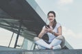 Woman in sportswear sitting in city street, relax after sports training, use smartphone, listen to music, checking email Royalty Free Stock Photo