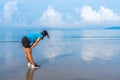 Woman in sportswear streching and preparing to run at the beach with blue sea and beautiful sky background Royalty Free Stock Photo