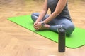 Woman in sporty outfit relaxing meditating sitting on mat with hands on bare feet, doing butterfly yoga exercise, stretching