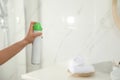 Woman spraying air freshener in bathroom