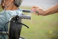 Woman is spraying alcohol,disinfectant spray on wheelchair handlebar hand,prevent infection,pandemic of Covid-19,spread of