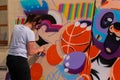 Woman spraying paint from can on wooden surface at graffiti festival