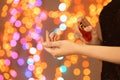 Woman spraying perfume on wrist against blurred lights