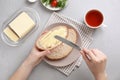 Woman spreading butter on slice of bread over table