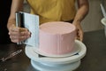 Woman spreads pink cream on cake, close-up. Cake making process, Selective focus Royalty Free Stock Photo